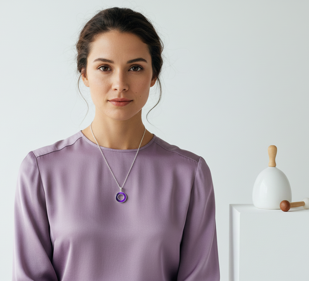 Woman wearing a purple pendant necklace against a plain background