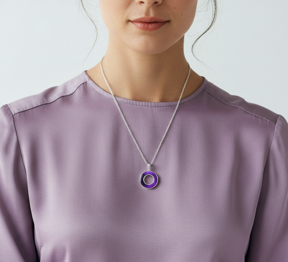 Person wearing a necklace with a purple pendant on a plain background