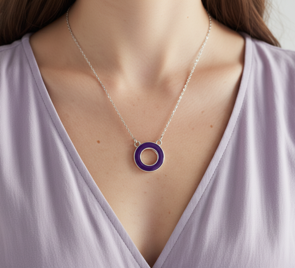 Necklace with a purple pendant worn by a person in a light purple top.