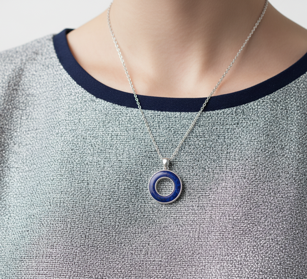 Necklace with a blue pendant on a person wearing a gray sweater.